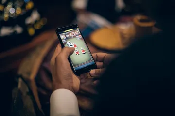 A man celebrating a winning moment on his laptop while gaming symbols float around him, capturing the excitement of ZBZBET games.